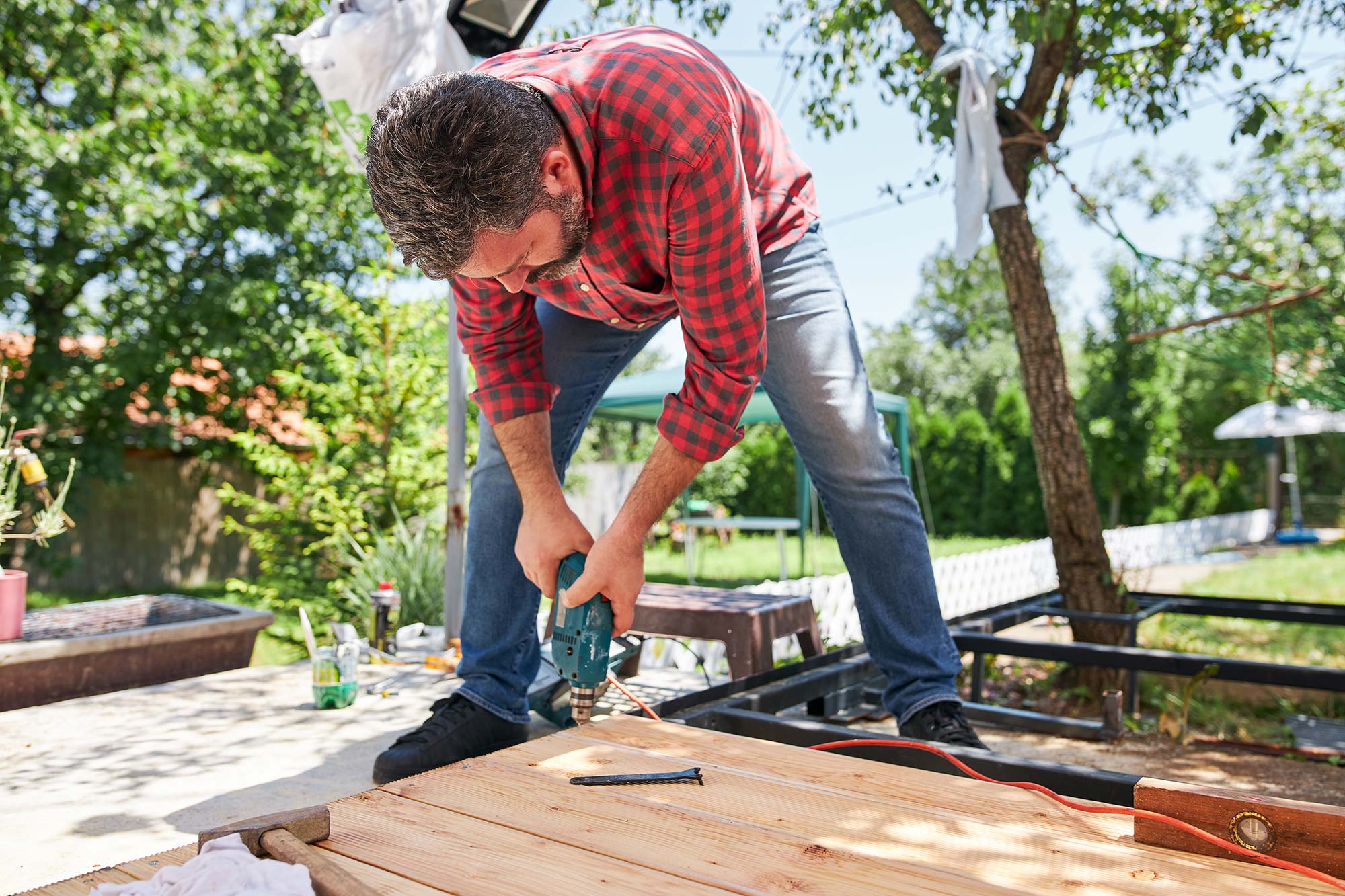 Man skruvar i en trädgård.