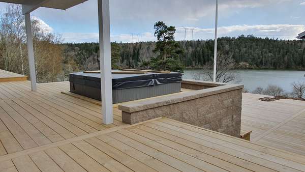 Jacuzzi med ett stort trädeck byggt runtomkring med en fantastisk sjöutsikt.