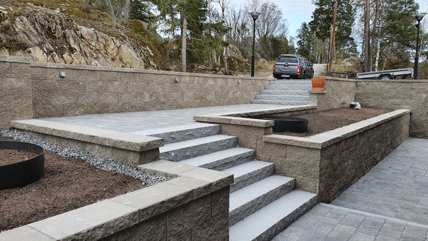 Stilren entré till hus som består av trappor, stödmurar och belysning.